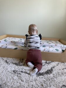 Baby kneeling by the bed